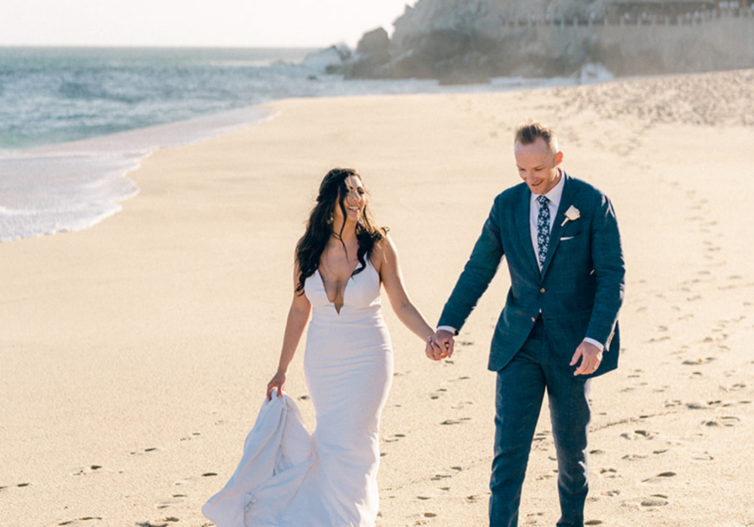 couple walk hand in hand on beach